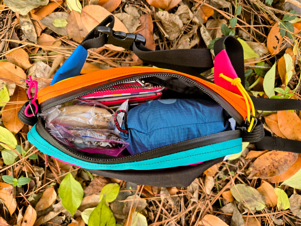 an unzipped atom roo fanny pack on the ground in the fall