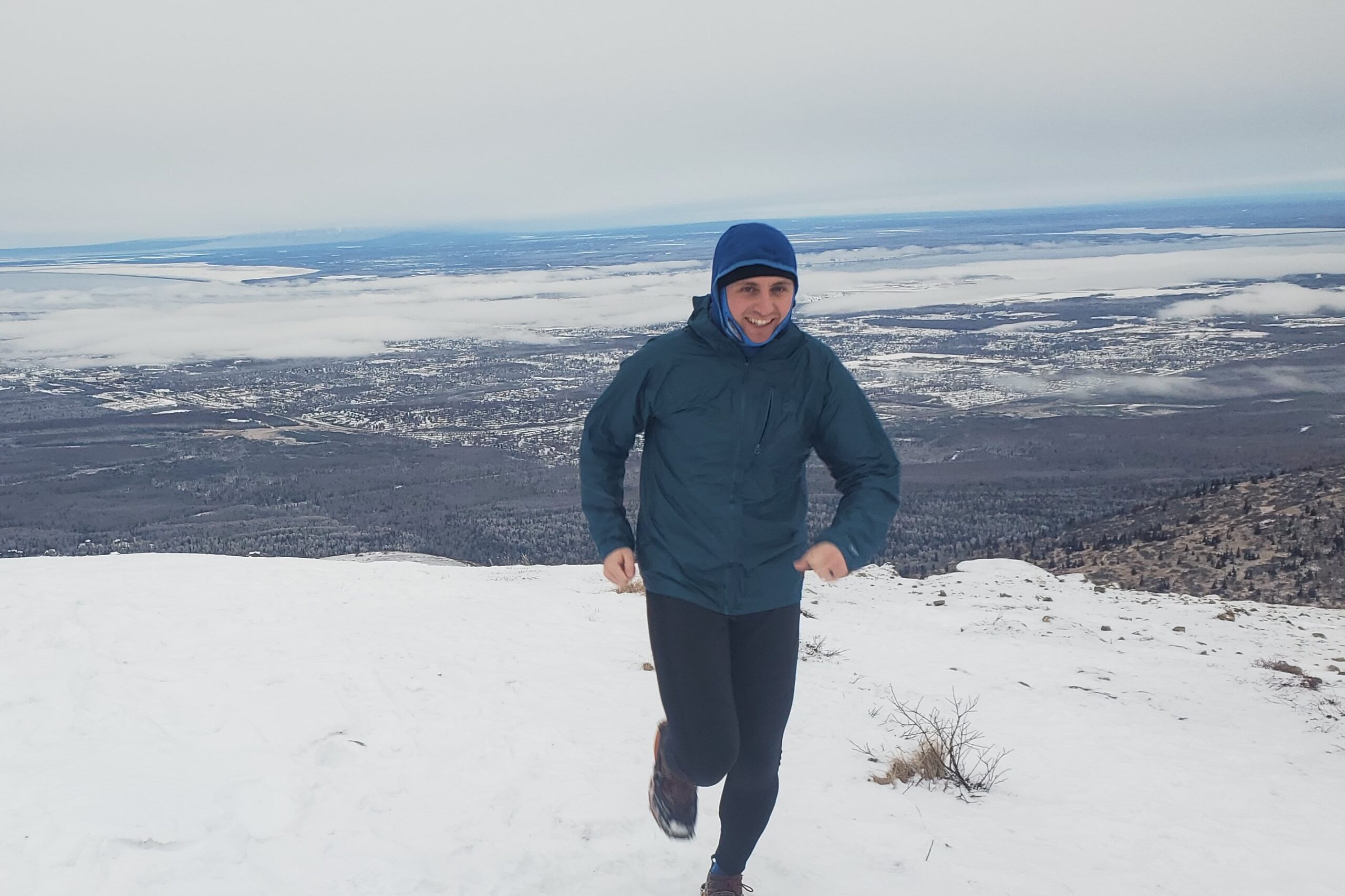 A man runs up a snowy mountain trail