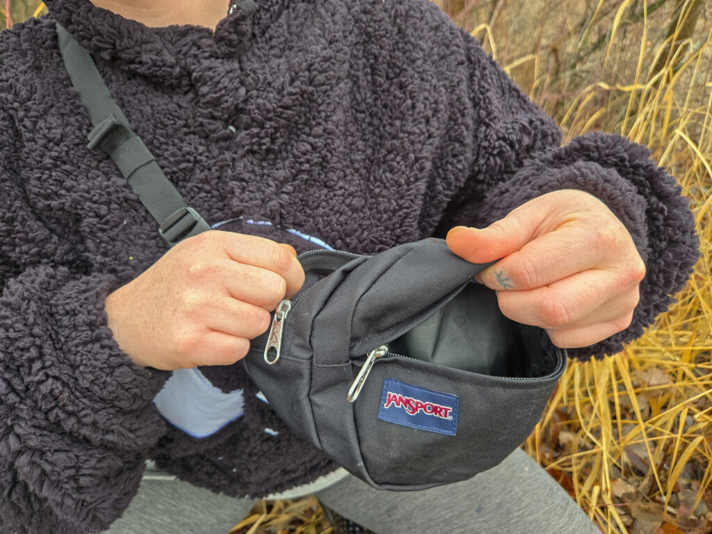 woman unzipping the jansport 5th avenue fanny pack