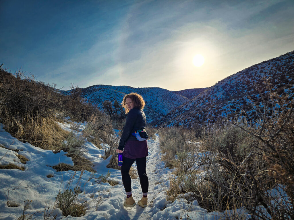 woman walking on a snowy desert trail with a fanny pack on
