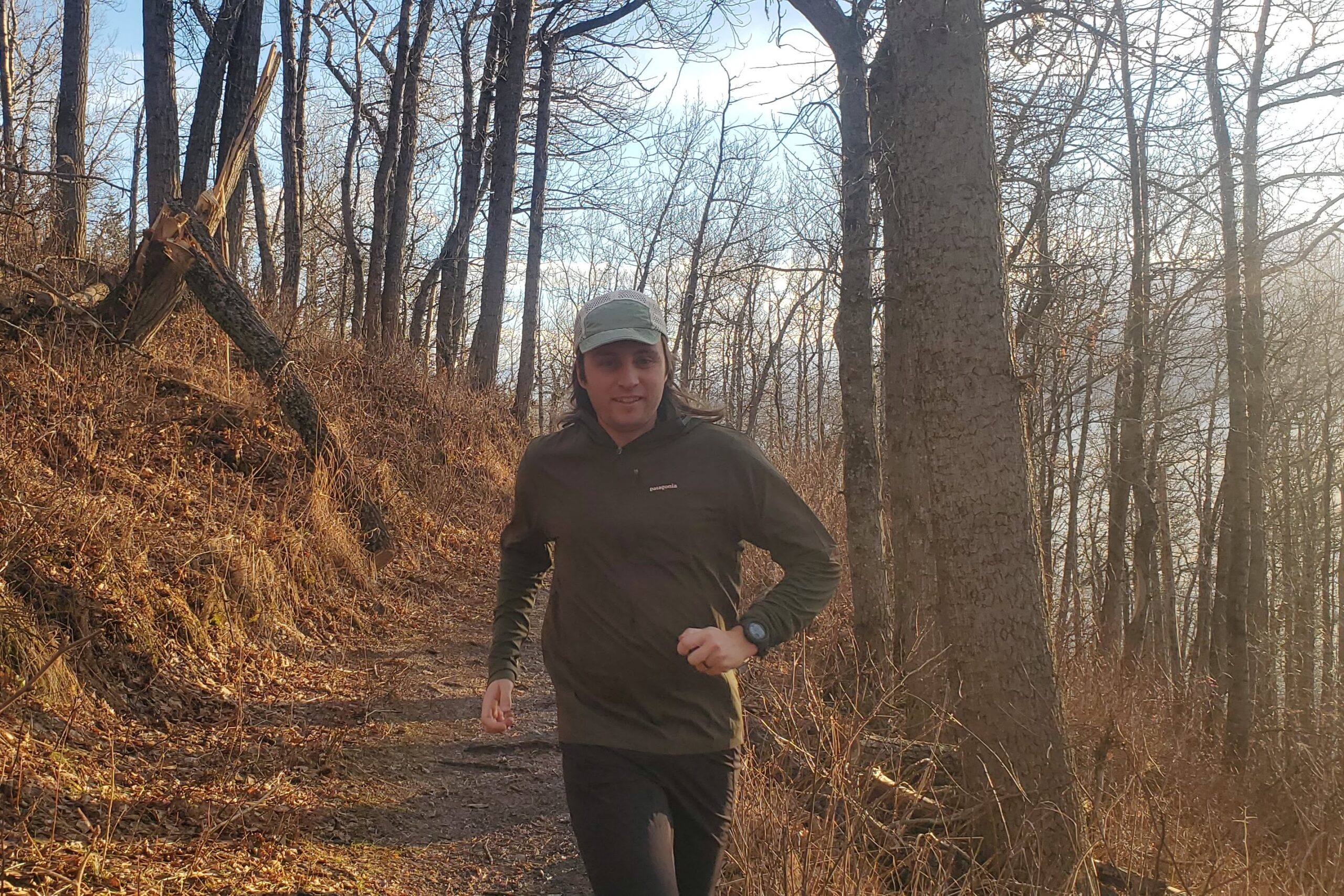 A man runs down a forest trail wearing a GPS watch.