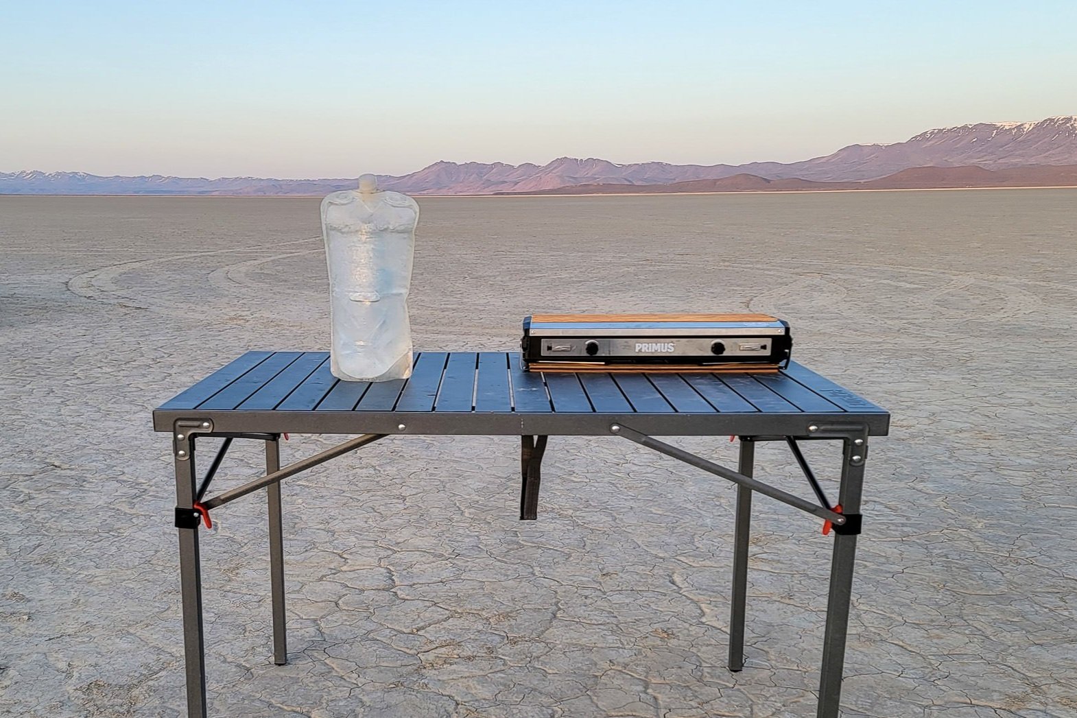 table and stove and water set up in a desert