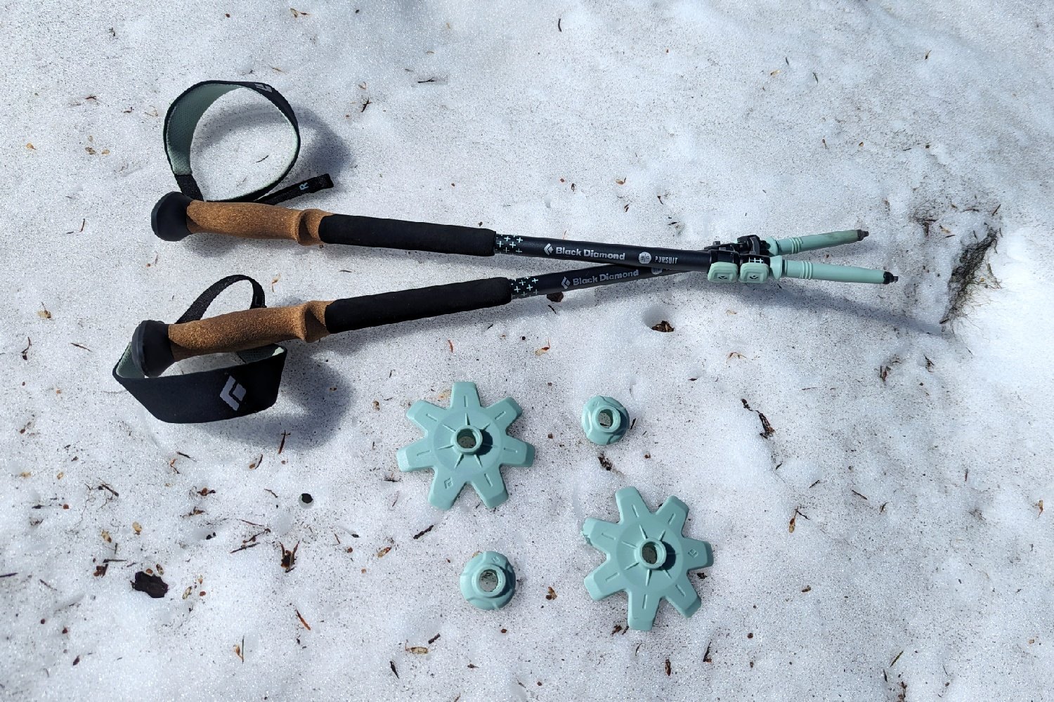 collapsed trekking poles with the two types of baskets resting on the snow