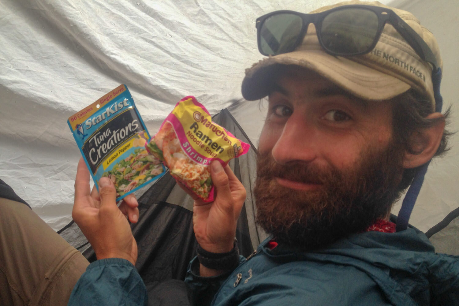 backpacker holding up a tuna packet and ramen noodle package