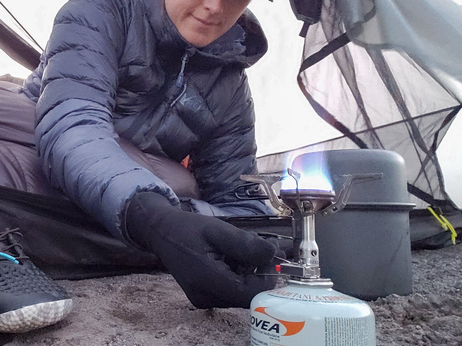 backpacker starting a backpacking stove near a tent