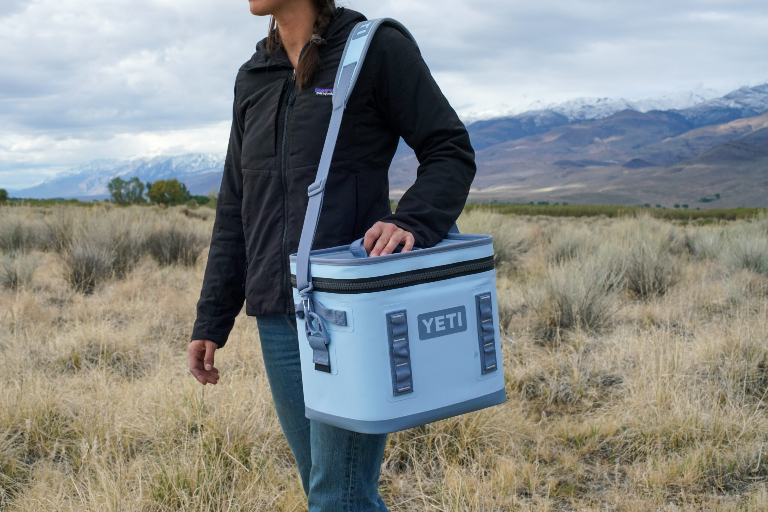 A person carries the YETI Hopper Flip 12 using the shoulder strap. Their face is not visible.