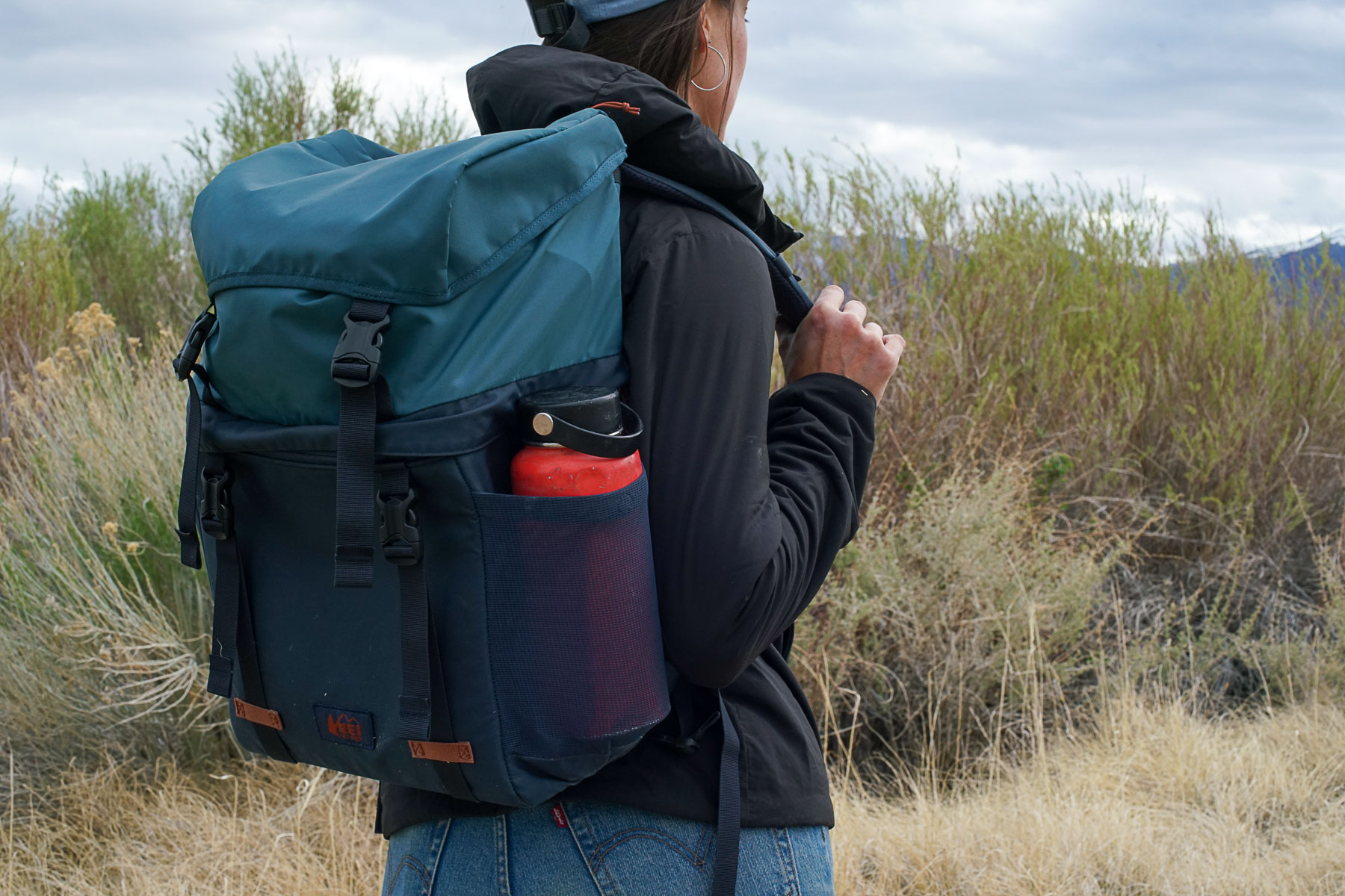 A person with their back to the camera walks with the REI Cool Trail Split Pack on their back.