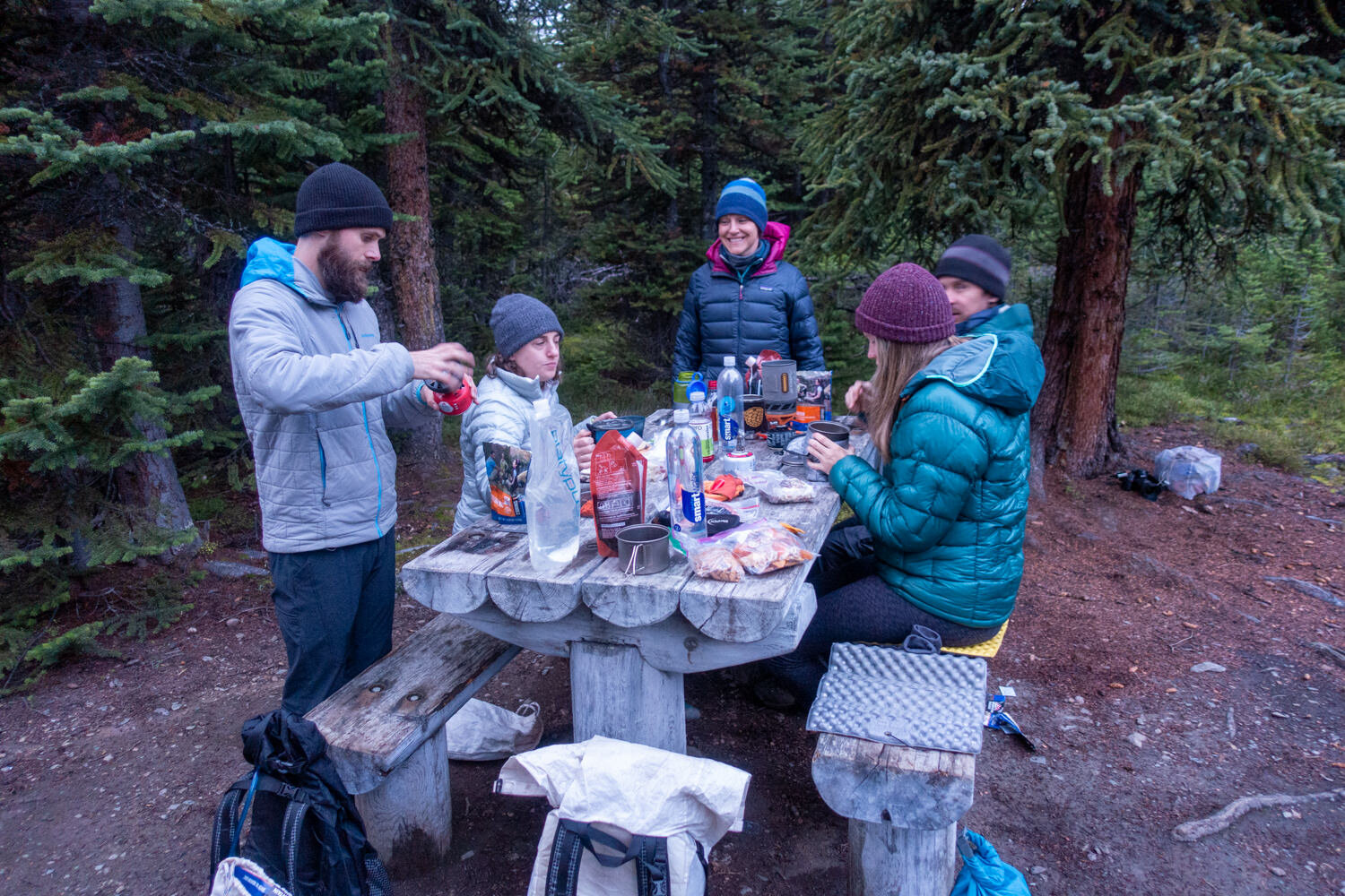 group of people eating at a campsite picnic table