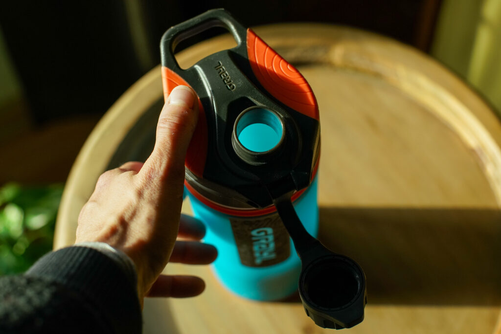 A top down view of the Grayl GeoPress water bottle's lid. A person's thumb presses on the grip portion of the lid.
