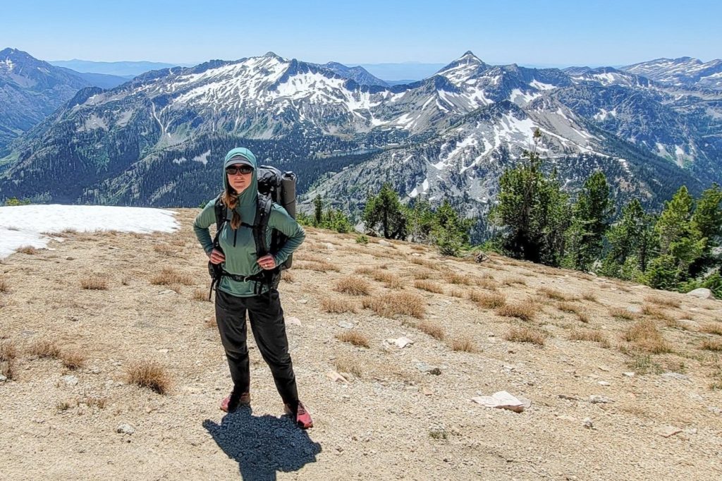 a backpacker posing while wearing sun shirt on a view over the mountains
