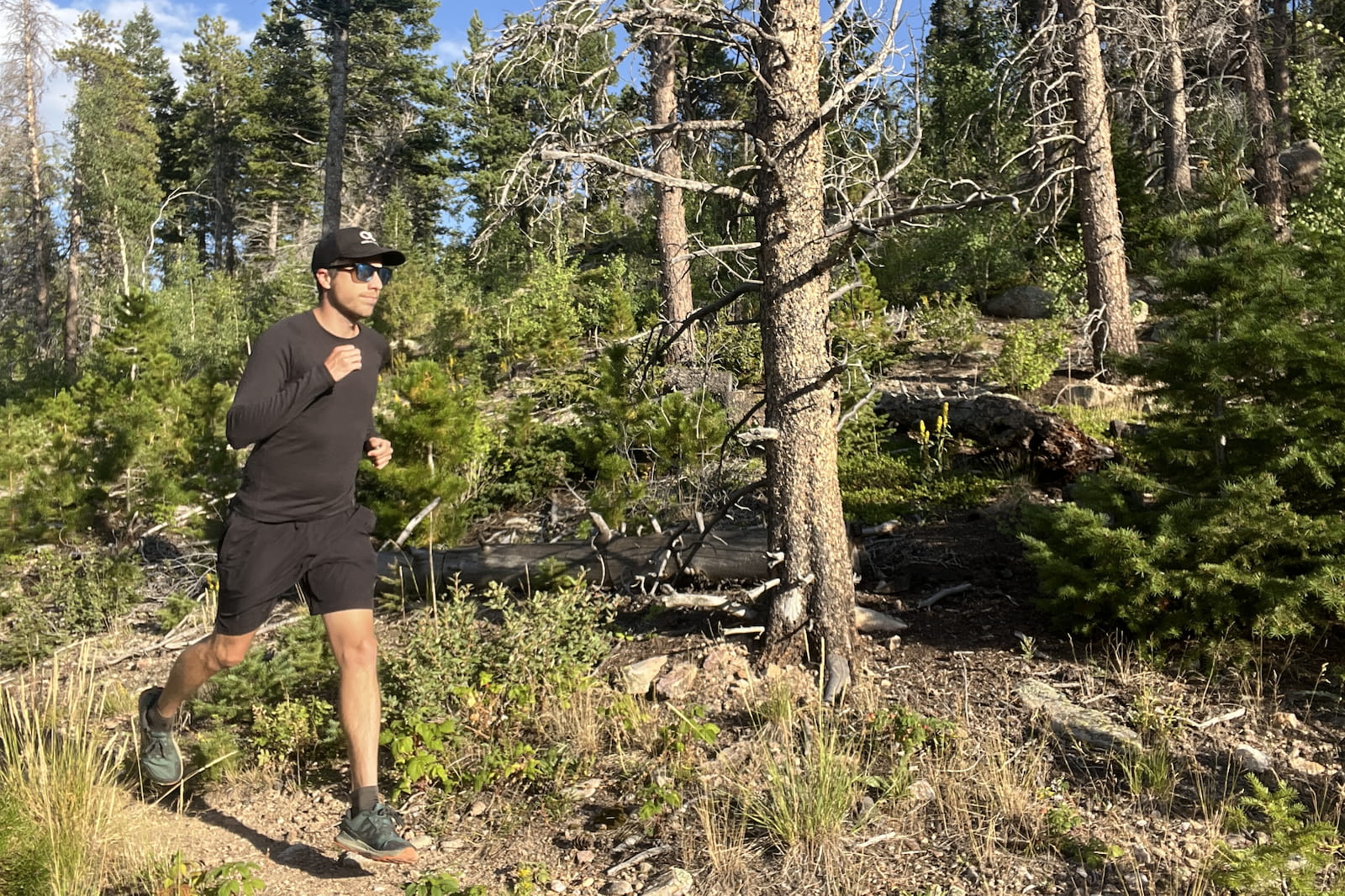 a runner runs along a wooded trail in a black base layer.