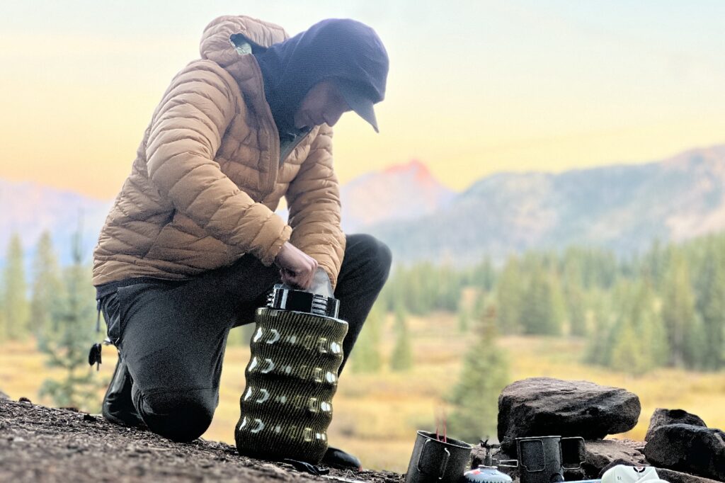 a hiker kneels to pack a bear canister