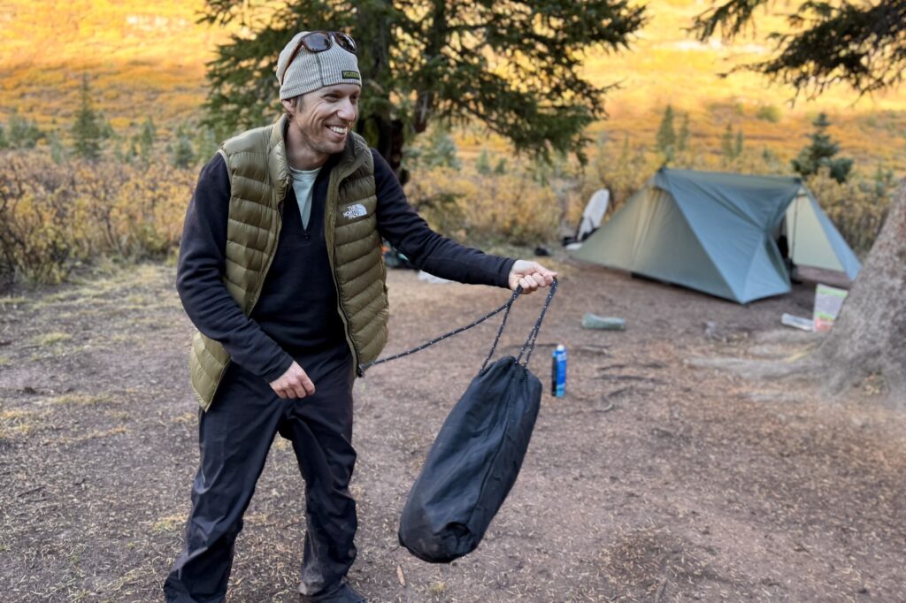 a hiker laughs as he swings around an ursack