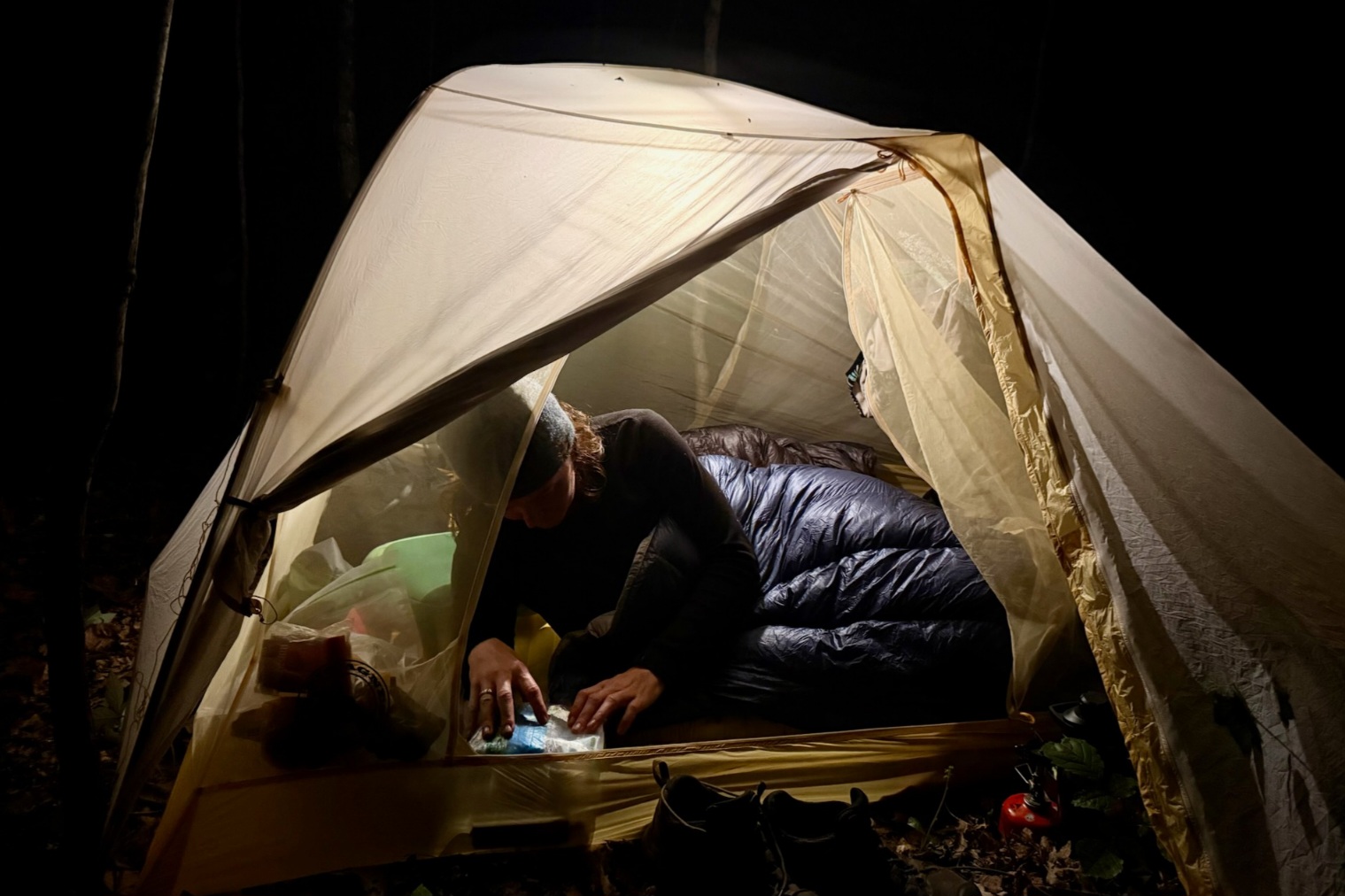 Hiker in a Hyperlite Mountain Gear 20-Degree Quilt in a tent at night