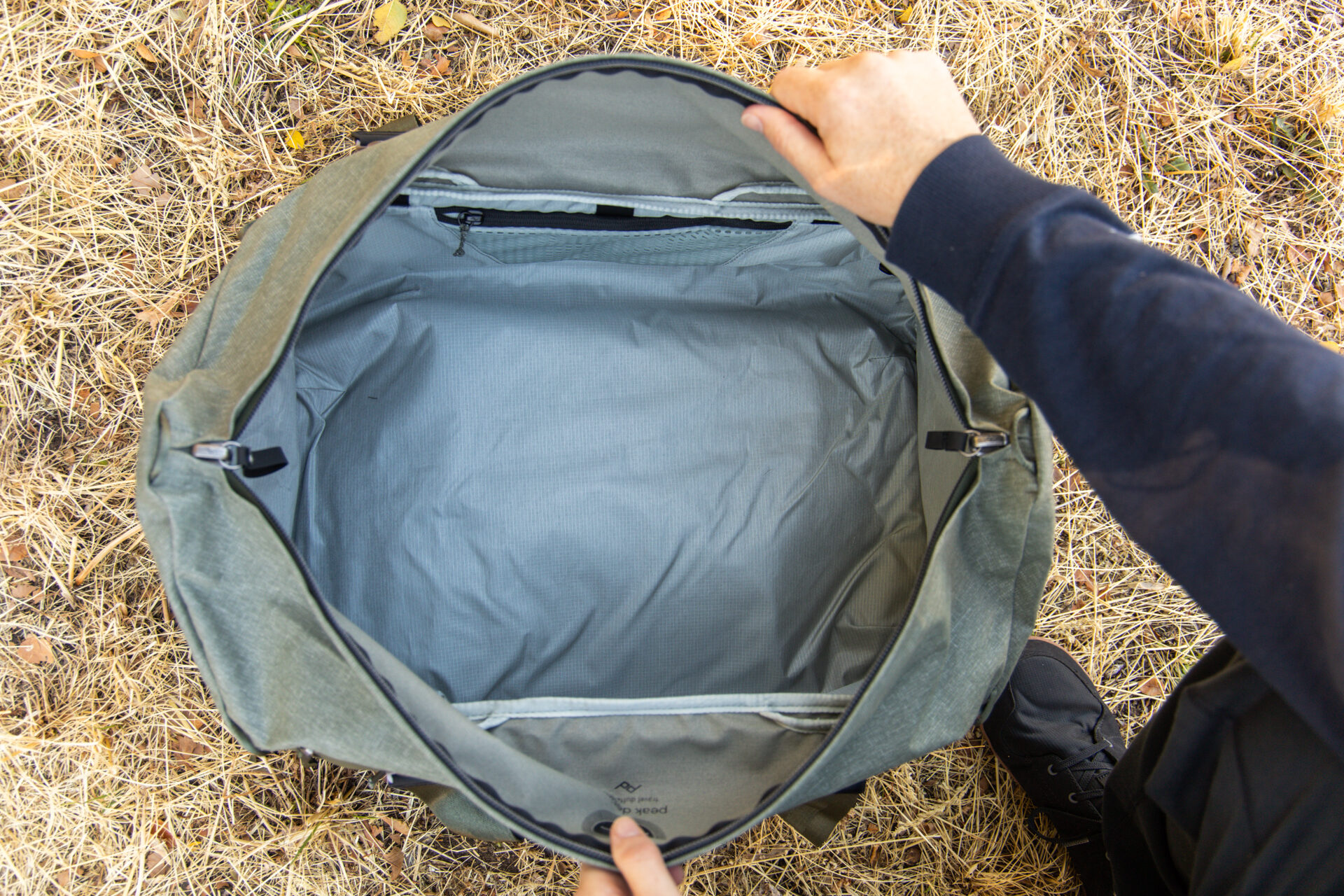 A man opens the mouth of the duffel wide.