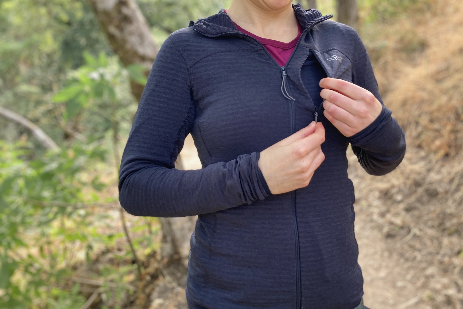A woman unzips the chest pocket on her fleece.