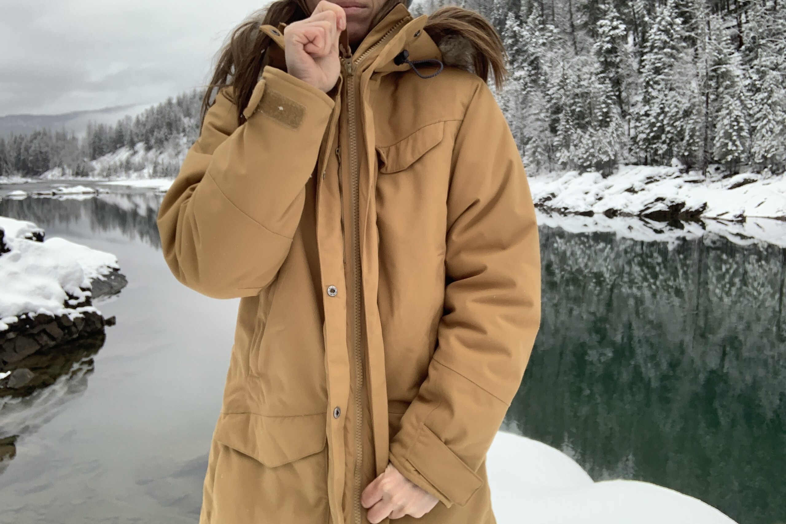 A woman zips the Fjallraven Nuuk in a wintry setting