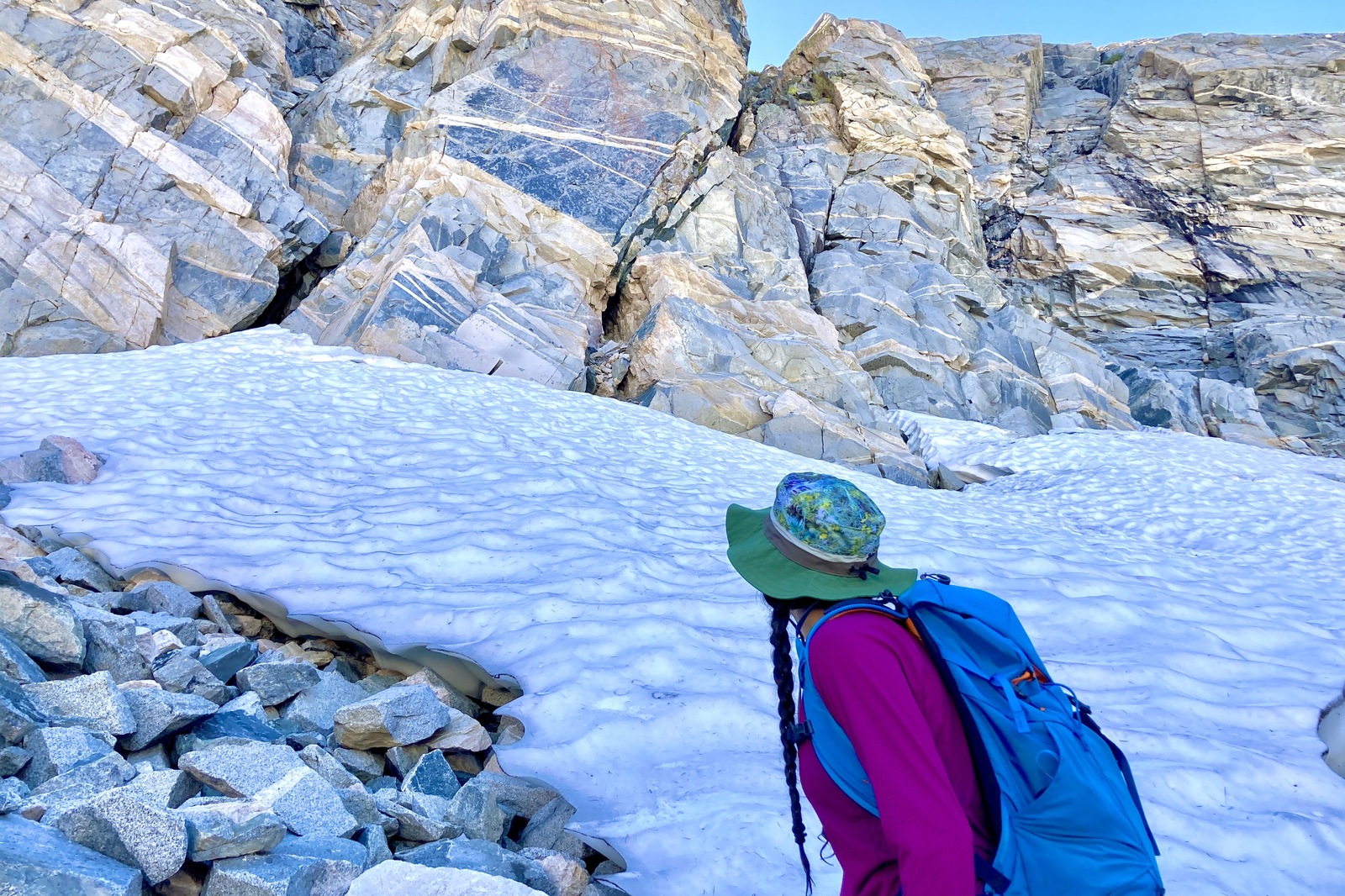 A woman hikes up a snowy slope on a mountain.