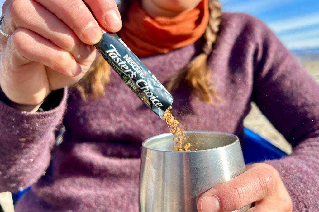 Up-close of a person pouring instant coffee out of a packet into a cup