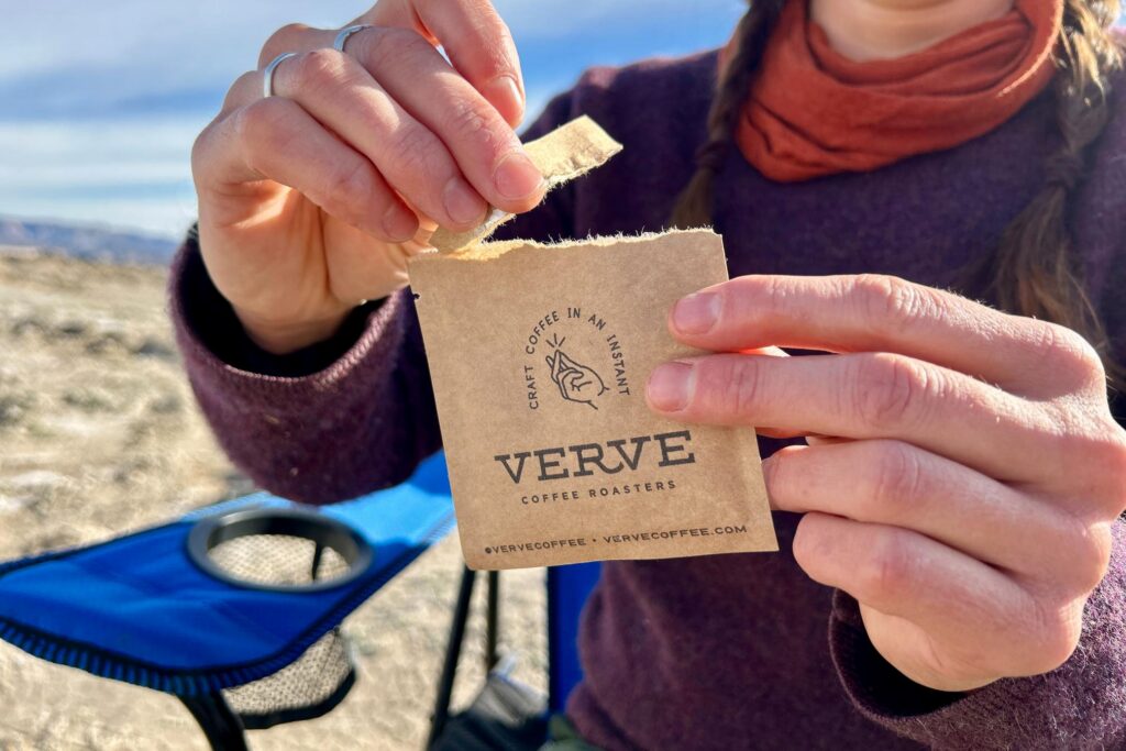 Up-close image of a person tearing the top of a packet of instant coffee