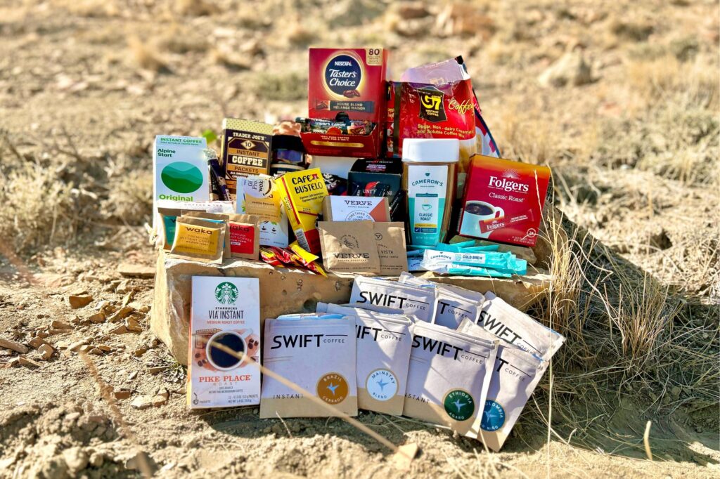 An image of 12 different instant coffee brands staged on a rock