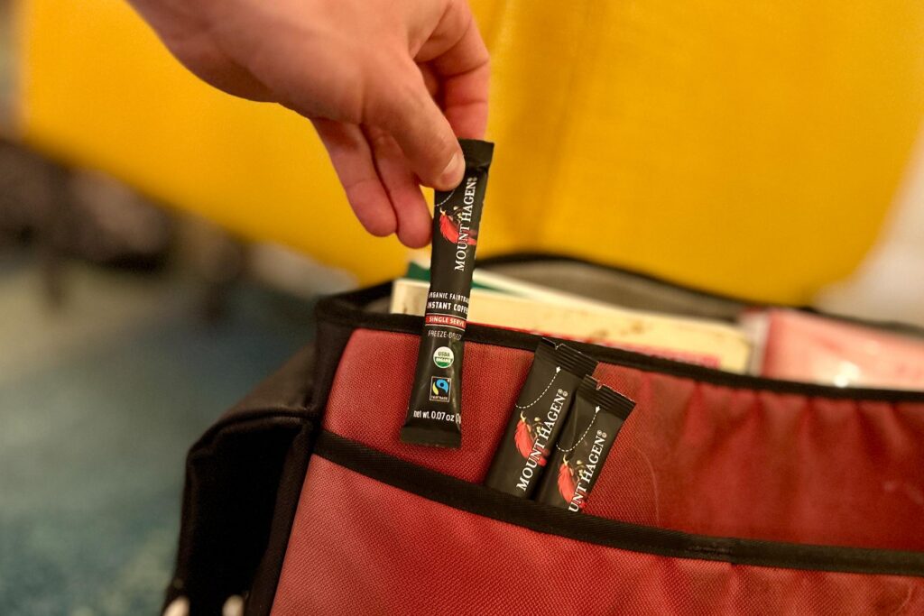 A hand pulling a packet of Mount Hagen instant coffee out of a briefcase pocket