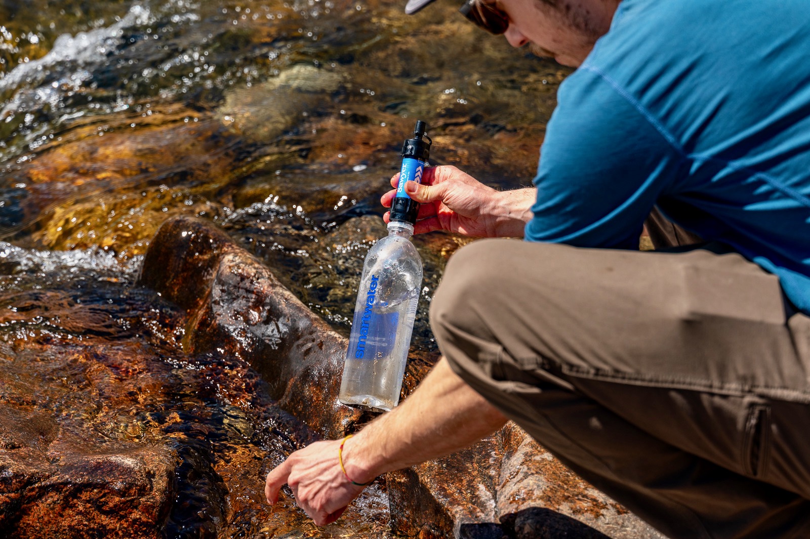 A hiker holds a smartwater bottle with the sawyer mini attached