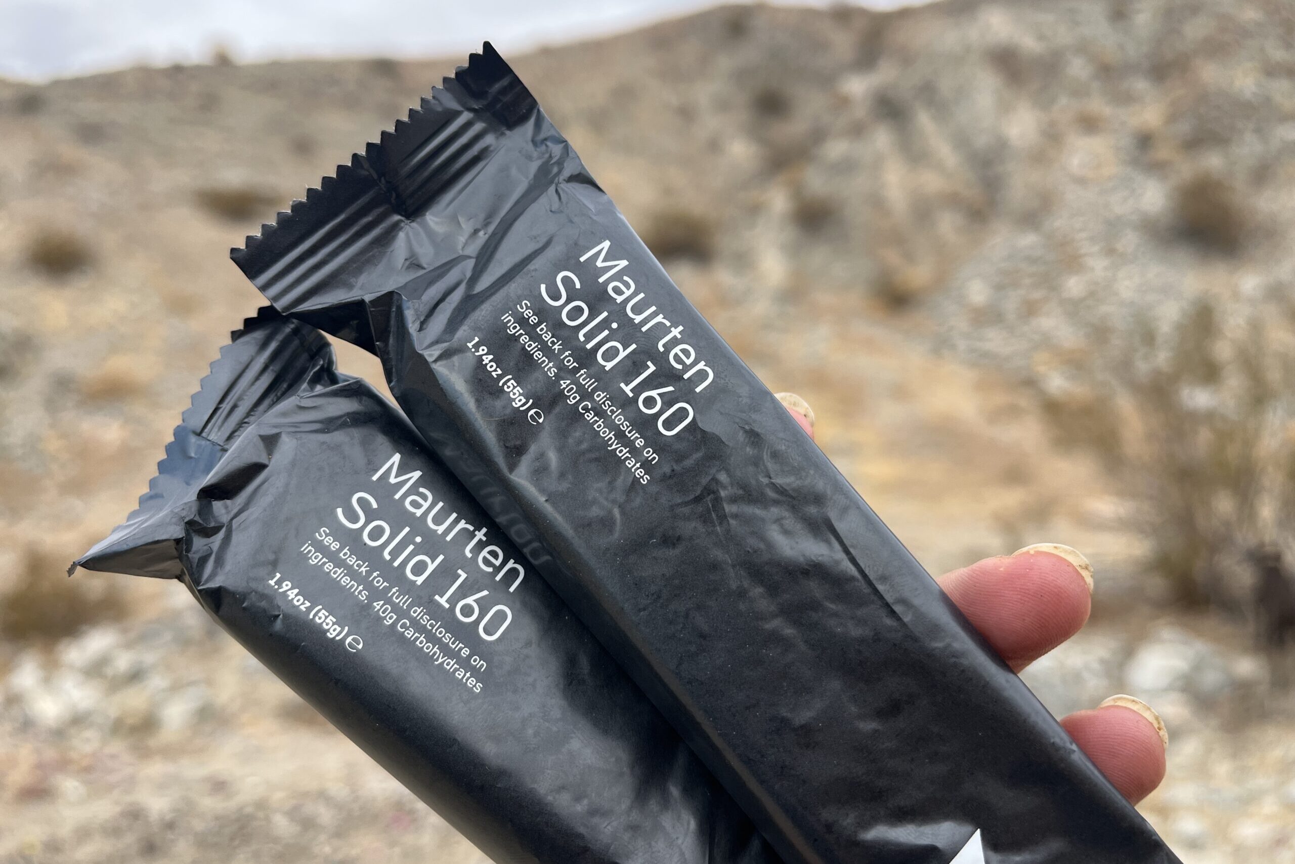 hand holding Maurten Solid 160 Bar in desert setting