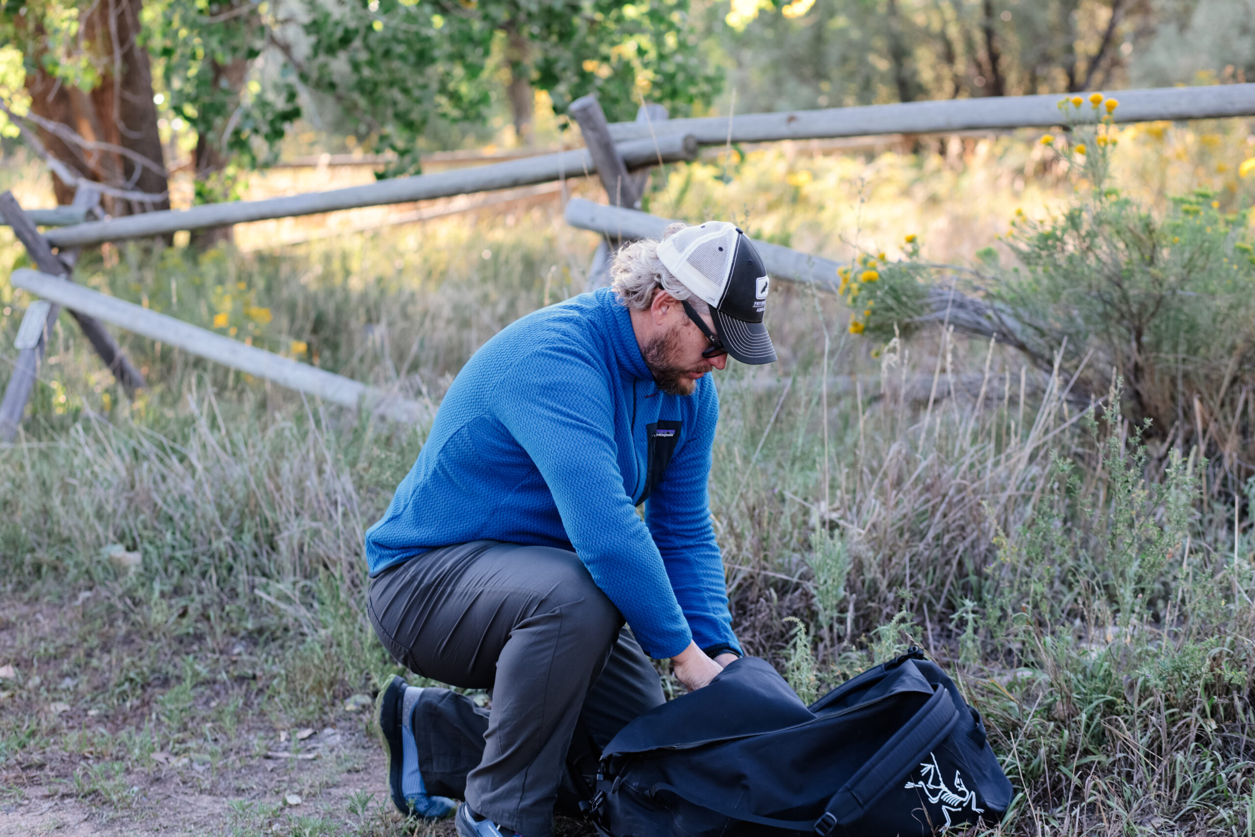 A man kneels to load a pack.