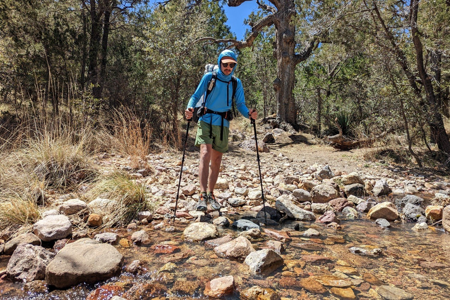 thru-hiker holding trekking poles about to cross a desert stream