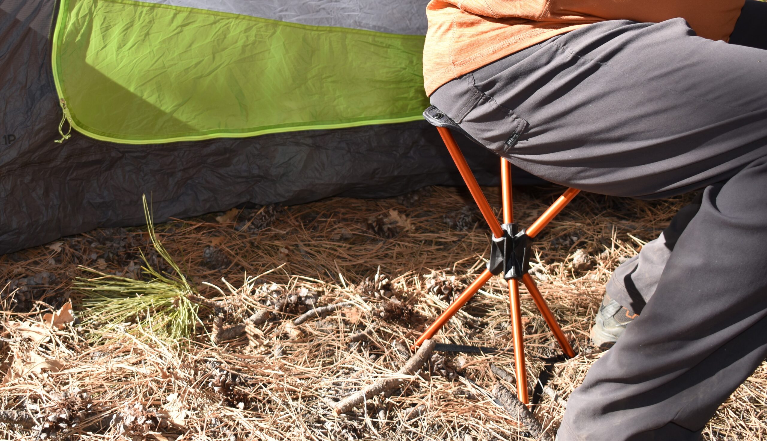 close up of a 200 lb backpacker sitting on the REI Flexlite Air Stool in front of his tent