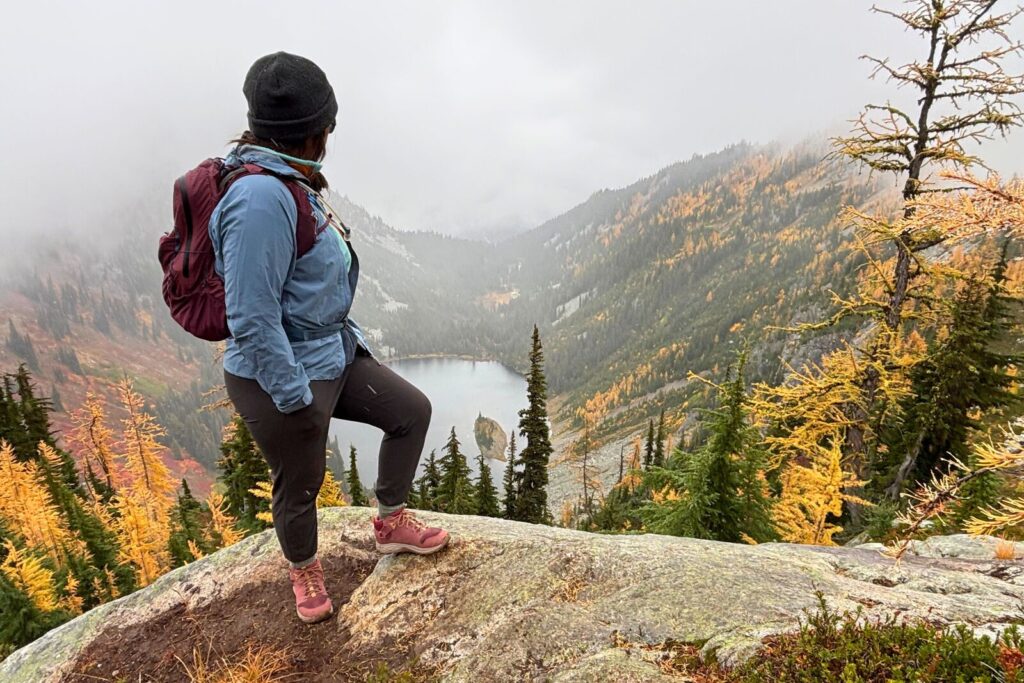 Hiker overlooking a lake wearing the Teva Grandview GTX Mid women’s hiking boots